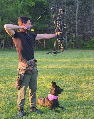Mike Haag Assistant Bow Tech Barefoot Archery drawing a bow with a dog by his feet