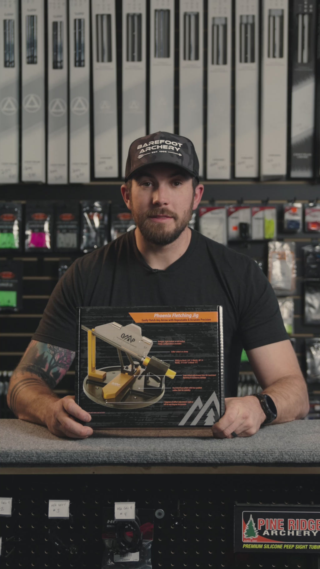 man in an archery shop behind the counter discussing the OMP fletching jig