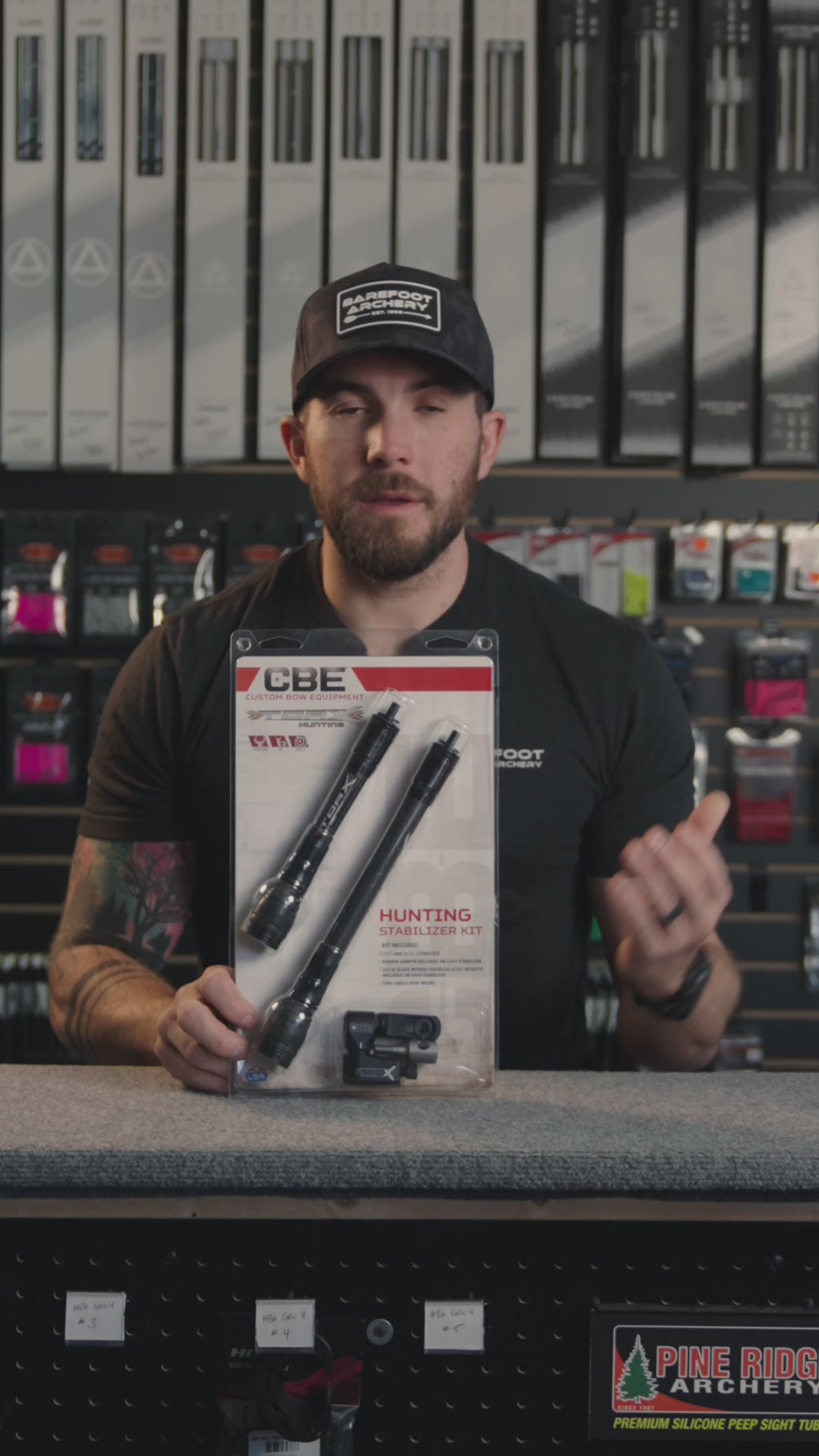 man in an archery shop behind the counter discussing the CBE hunting stabilizer kit