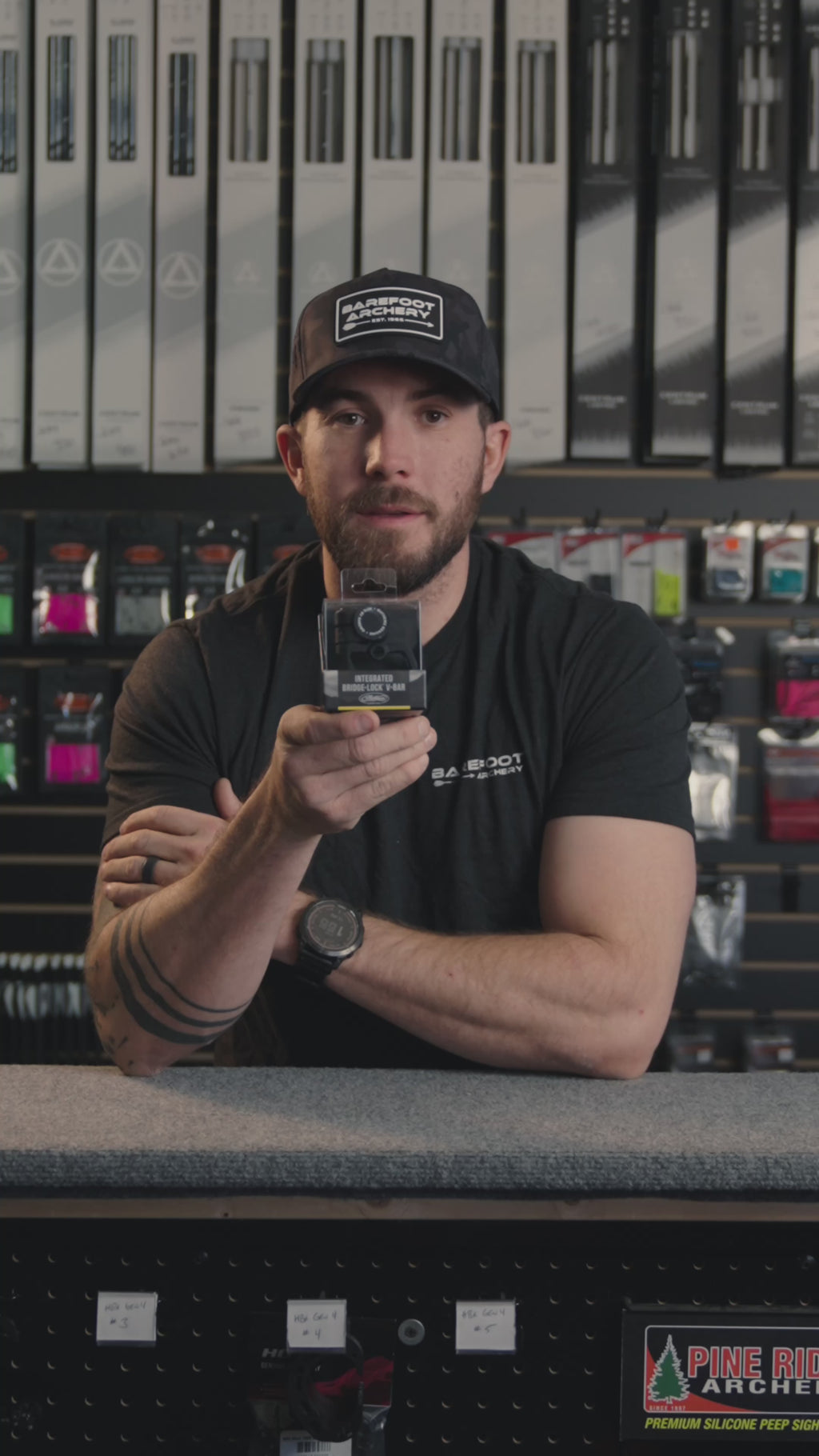 man in an archery shop behind the counter discussing the Mathews bridgelock integrated v bar